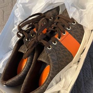 Micheal Kors orange and brown sneakers with laces.